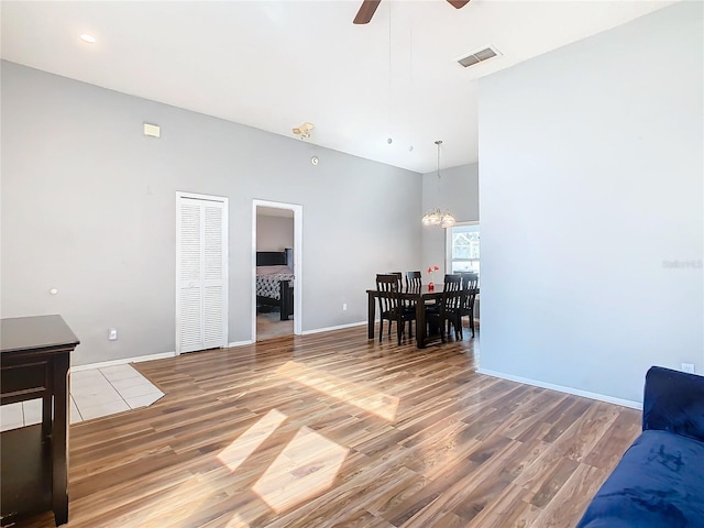 living area with ceiling fan with notable chandelier, baseboards, visible vents, and light wood-style floors