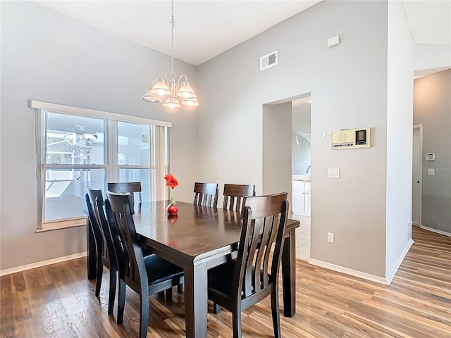 dining room featuring a chandelier, light wood-type flooring, visible vents, and baseboards