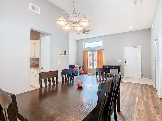 dining space featuring light wood-style floors, visible vents, and ceiling fan with notable chandelier