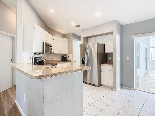 kitchen featuring visible vents, a peninsula, stainless steel appliances, light countertops, and white cabinetry