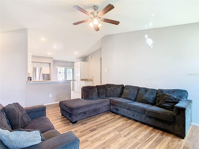 living area with lofted ceiling, ceiling fan, light wood-style flooring, and baseboards