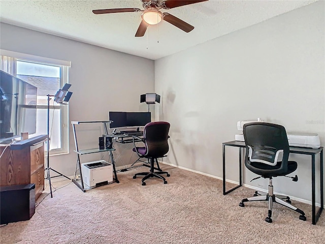 carpeted office space featuring a textured ceiling, a ceiling fan, and baseboards