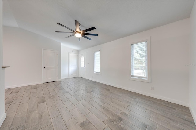 empty room featuring lofted ceiling, ceiling fan, baseboards, and wood finished floors