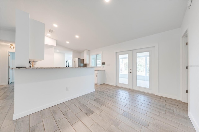 kitchen featuring recessed lighting, white cabinetry, french doors, freestanding refrigerator, and light stone countertops