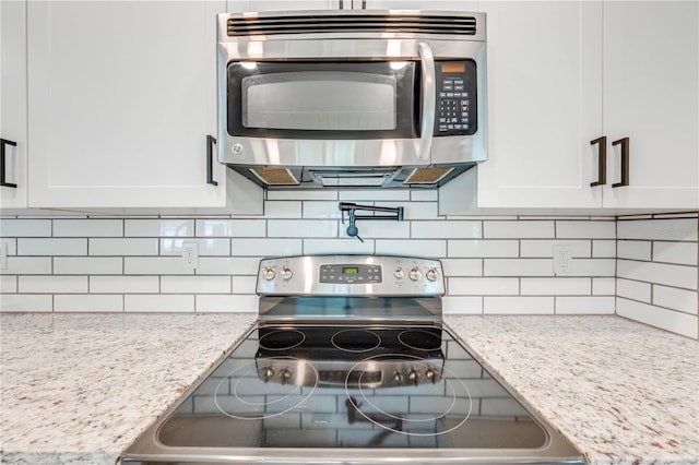 kitchen featuring appliances with stainless steel finishes, light stone countertops, white cabinets, and tasteful backsplash