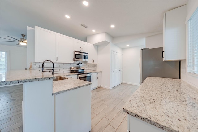 kitchen featuring tasteful backsplash, visible vents, a peninsula, stainless steel appliances, and a sink