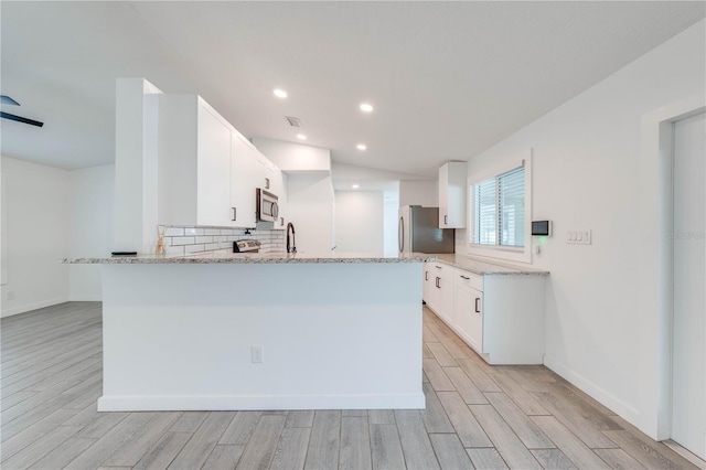 kitchen featuring light stone counters, wood finish floors, white cabinets, appliances with stainless steel finishes, and decorative backsplash