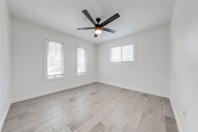 empty room featuring light wood-type flooring, baseboards, and a ceiling fan