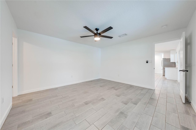 empty room with light wood-type flooring, visible vents, ceiling fan, and baseboards