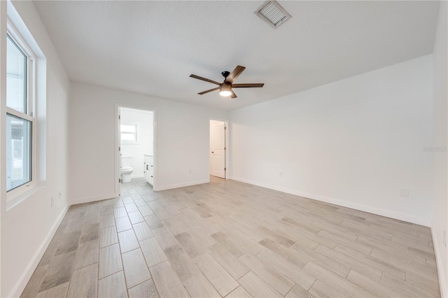 empty room featuring light wood-style floors, baseboards, and visible vents