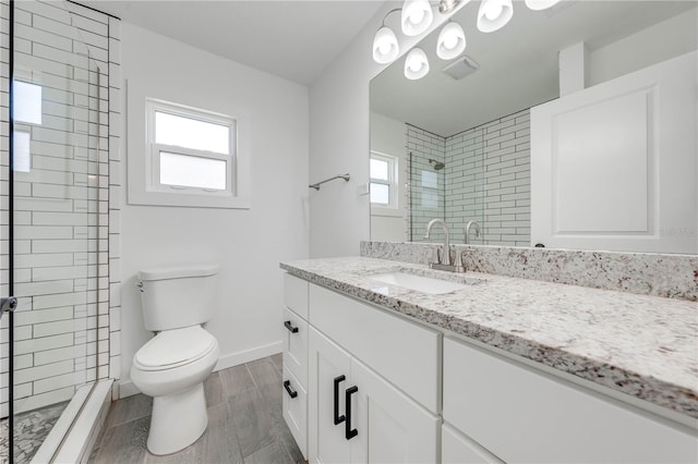 bathroom with toilet, wood finish floors, vanity, baseboards, and a shower stall