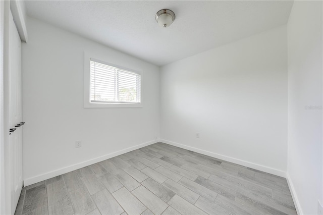 spare room with baseboards and light wood finished floors