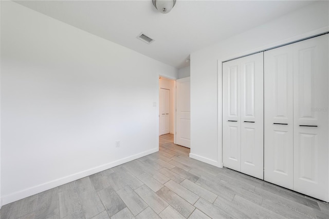 unfurnished bedroom featuring a closet, visible vents, light wood-style flooring, and baseboards