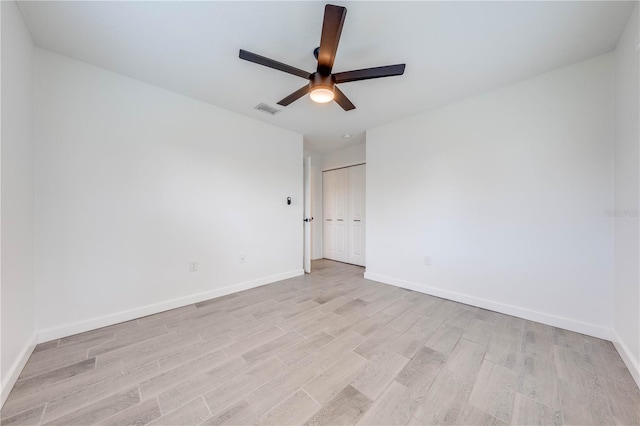 spare room featuring baseboards, a ceiling fan, visible vents, and light wood-style floors