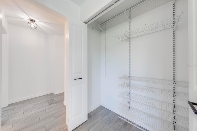 walk in closet with wood finished floors