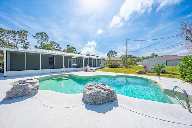 outdoor pool featuring a sunroom, an outdoor structure, a lawn, and a patio