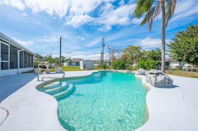 pool featuring an outbuilding, a sunroom, a patio area, fence, and a shed