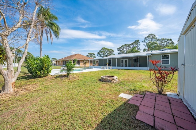 view of yard with a sunroom, an outdoor pool, and a fire pit