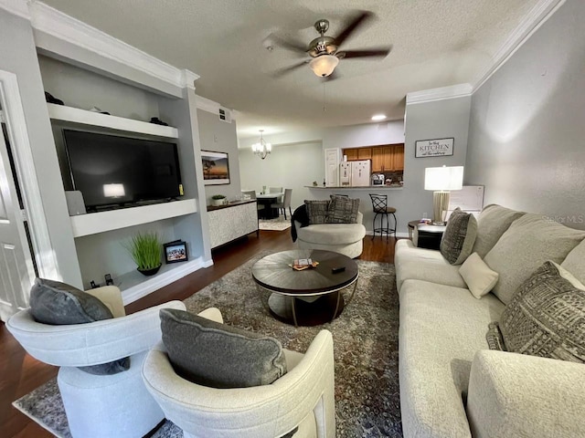 living room featuring built in shelves, dark wood-type flooring, ornamental molding, a textured ceiling, and ceiling fan with notable chandelier