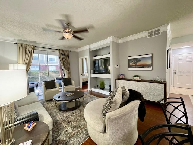 living area featuring crown molding, visible vents, a ceiling fan, a textured ceiling, and wood finished floors