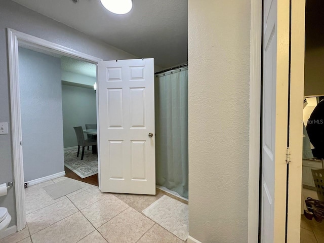 full bathroom featuring a shower with curtain, baseboards, toilet, and tile patterned floors