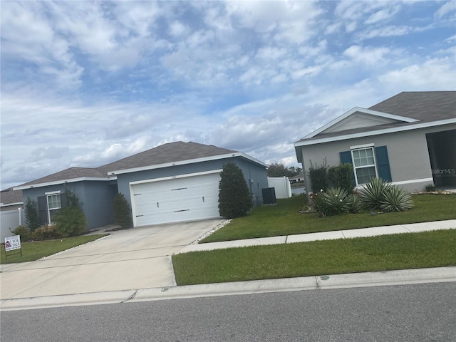 view of front of house featuring a garage, concrete driveway, a front lawn, and stucco siding