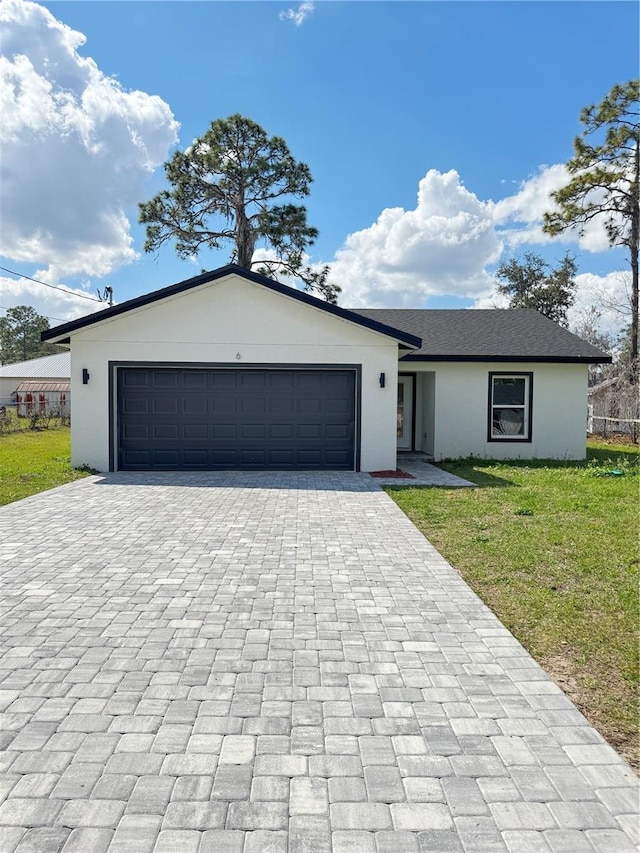 ranch-style house with a garage, a front yard, decorative driveway, and stucco siding