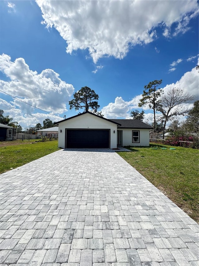 view of front of home with an attached garage, a front lawn, decorative driveway, and stucco siding