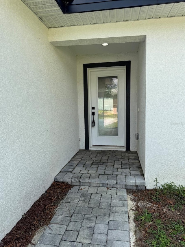 doorway to property with roof with shingles and stucco siding