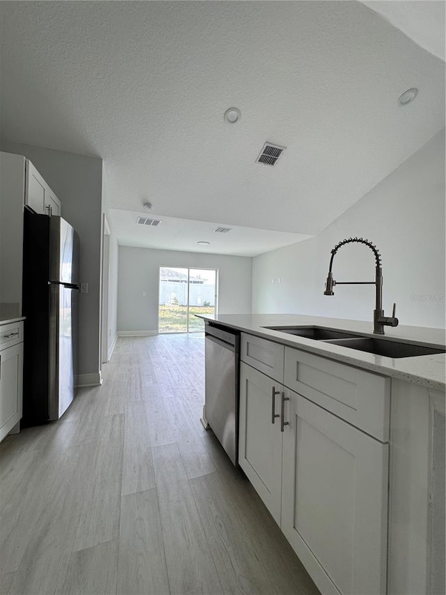 kitchen with light wood-type flooring, visible vents, appliances with stainless steel finishes, and a sink