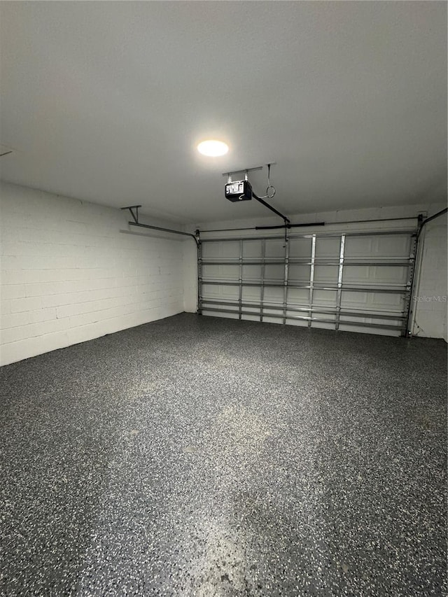 garage with concrete block wall and a garage door opener