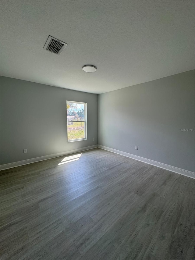 spare room featuring baseboards, visible vents, and dark wood-type flooring