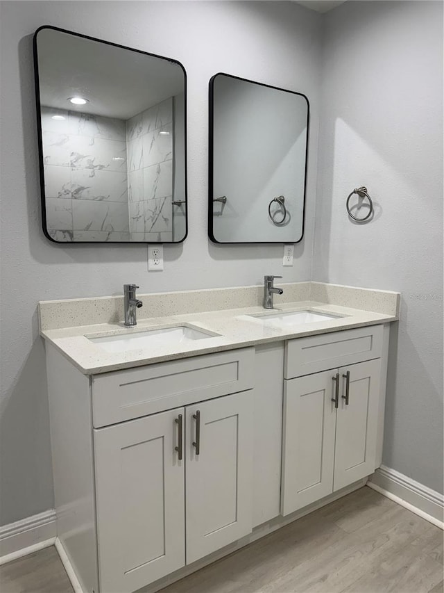 full bath featuring double vanity, a sink, and wood finished floors