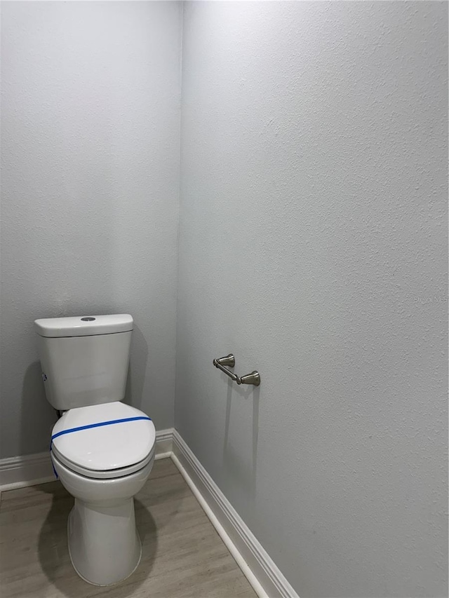 bathroom featuring wood finished floors, toilet, and baseboards