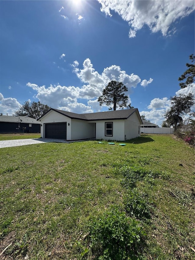 ranch-style house with an attached garage, fence, concrete driveway, stucco siding, and a front yard