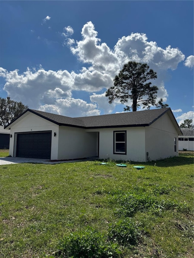 view of front of house featuring a garage, driveway, a front lawn, and stucco siding