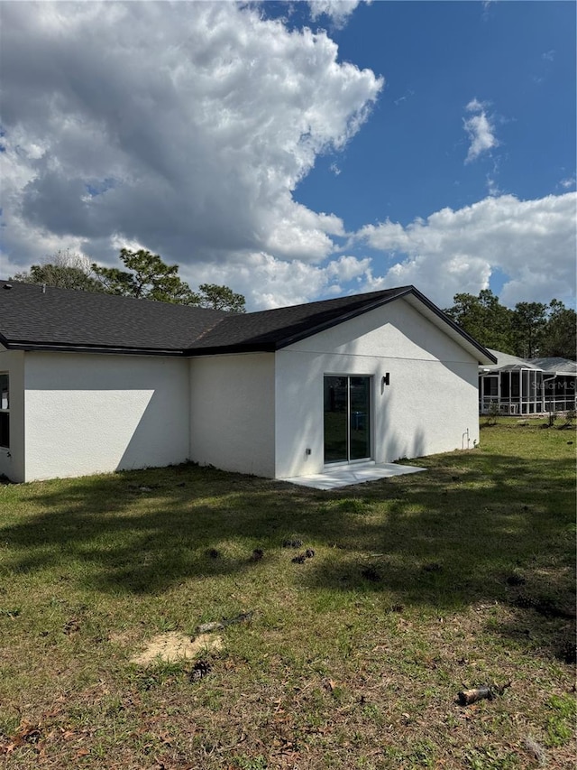 rear view of property featuring a yard and stucco siding