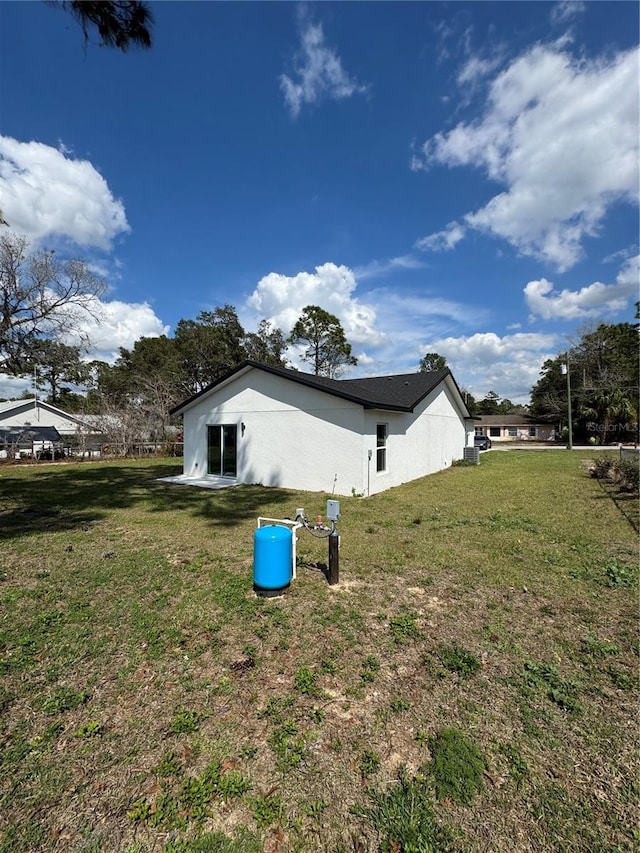 view of side of home featuring stucco siding and a yard