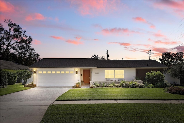 single story home with a garage, a yard, decorative driveway, and fence