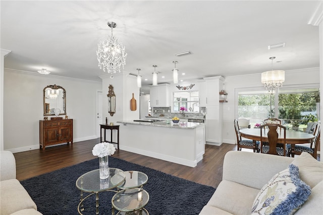 living area featuring ornamental molding, dark wood-style flooring, visible vents, and a notable chandelier