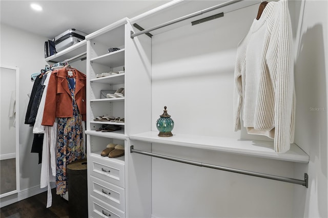 walk in closet with dark wood finished floors
