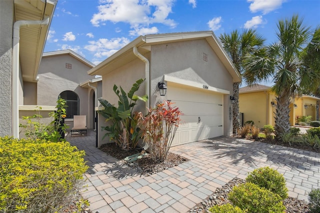 view of front facade with decorative driveway, an attached garage, and stucco siding