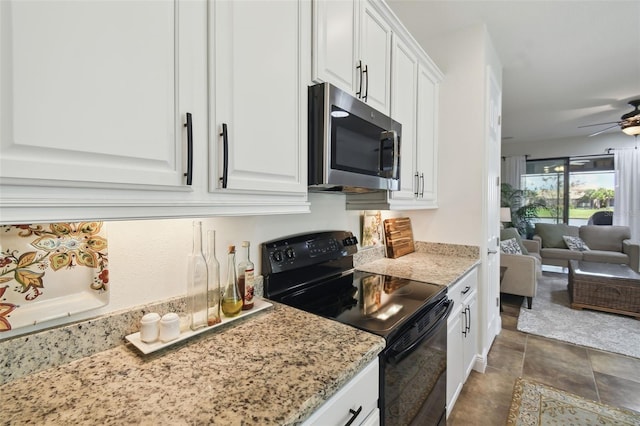 kitchen with a ceiling fan, stainless steel microwave, open floor plan, black range with electric stovetop, and white cabinetry