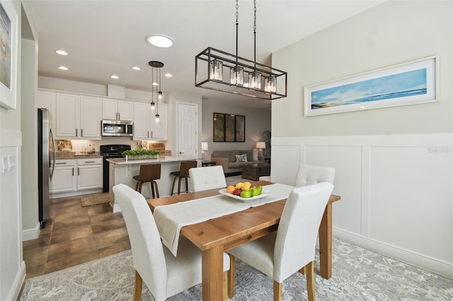 dining area featuring a wainscoted wall, recessed lighting, and a decorative wall