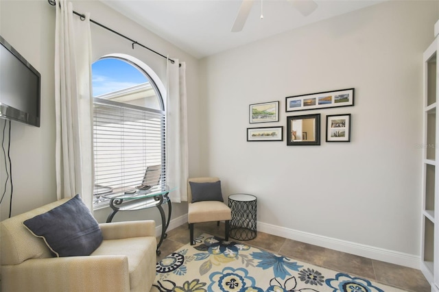 sitting room with ceiling fan, baseboards, and tile patterned floors