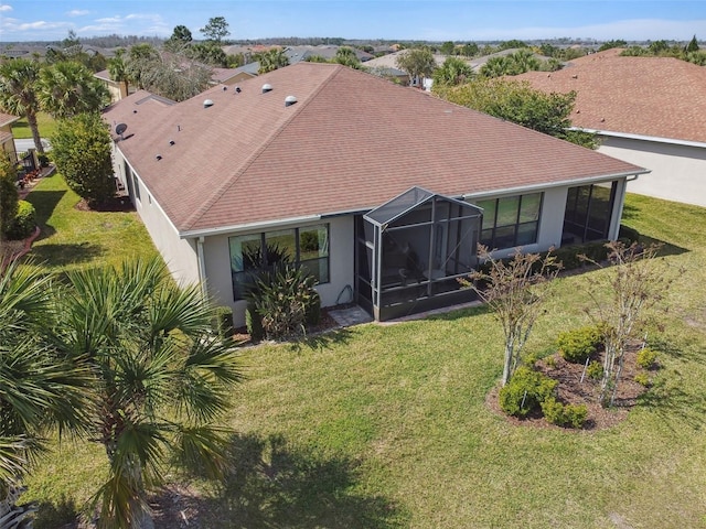 rear view of house featuring a lanai, a lawn, and stucco siding