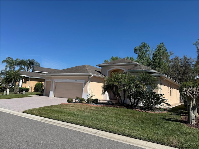 view of front of property with a garage, a front lawn, decorative driveway, and stucco siding