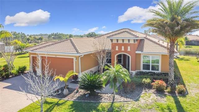 mediterranean / spanish house featuring a garage, a front yard, a tiled roof, and stucco siding