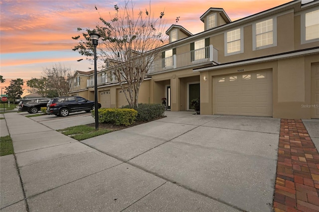 view of front of house with a garage, concrete driveway, a balcony, and stucco siding