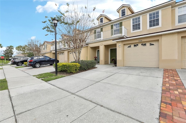 multi unit property with driveway, a garage, and stucco siding